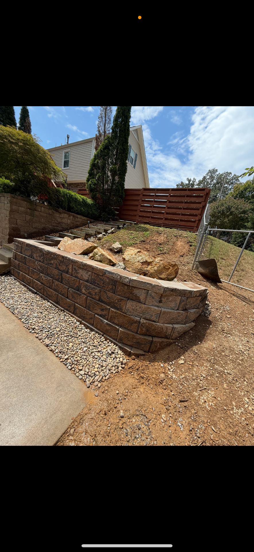 Brown retaining wall with wood privacy screen on a steep yard